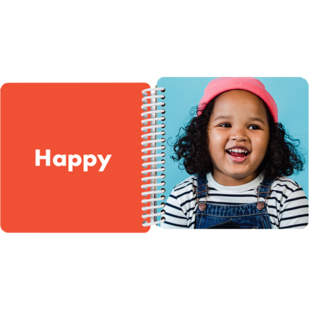 Child making a happy face in a personalized My Book of Emotions board book with the emotion "Happy"